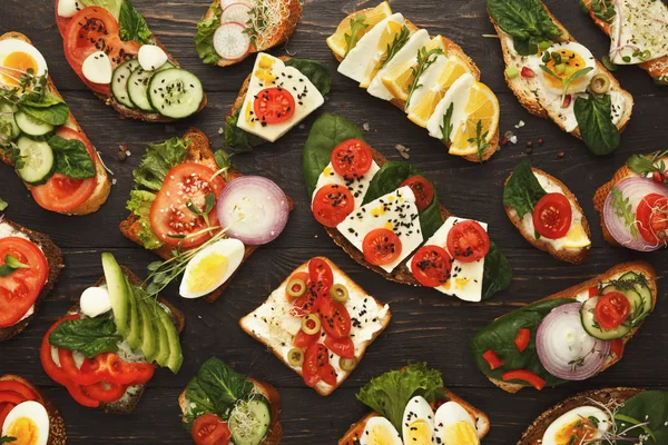 Variety of healthy vegetarian sandwiches on dark wood, top view — Stock Photo, Image