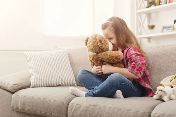 Šťastné děťátko ženské objímání její medvídek na gauči doma — Stock fotografie