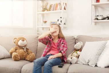 Evde kanepede otururken TV izlerken rahat küçük kız korkuyor