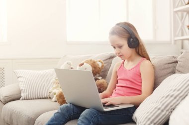 Ödev Kulaklığımda kanepede oturan laptop, sevimli küçük kız