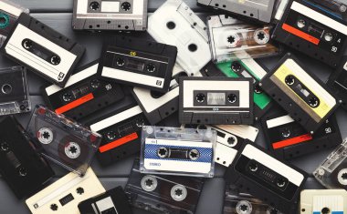 Heap of vintage audio cassettes at gray planks background clipart