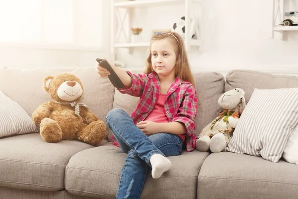 テレビを見ながら自宅のソファの上に座って美しいカジュアルな女の子 — ストック写真