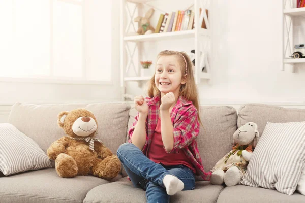 Krásné ležérní holčička, sledování televize, zatímco sedí na gauči doma — Stock fotografie