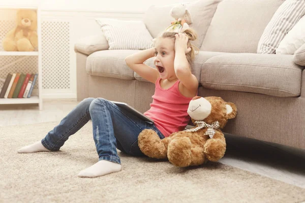 Liten flicka med tabletten sitter på golvet hemma — Stockfoto