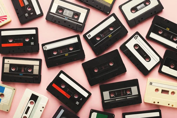 Haufen alter Audiokassetten auf rosa Hintergrund — Stockfoto