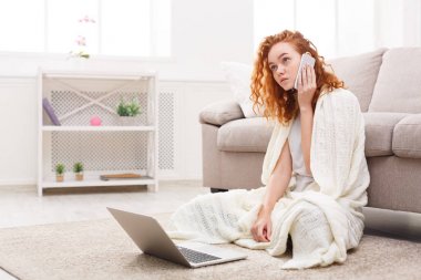 Evde boş vaktinizi. Dizüstü bilgisayar ve telefon kullanan dalgın kız