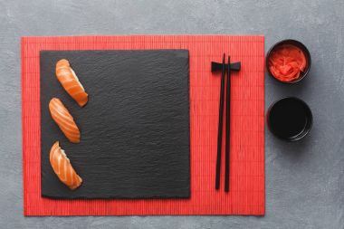 Sushi set and chopsticks on red mat, top view clipart