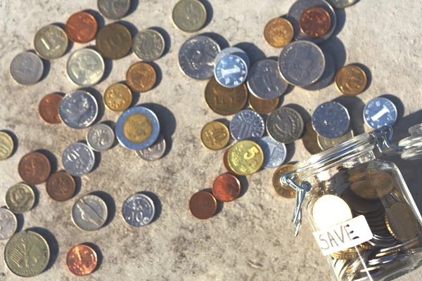 Суміш монет випадає зі скляної банки на підлозі — стокове фото