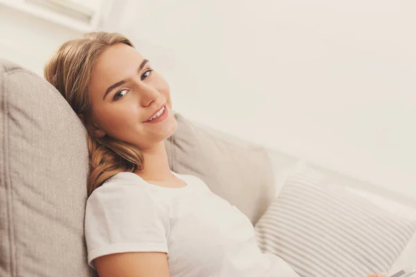 Mladá blond žena sedící na gauči béžové — Stock fotografie