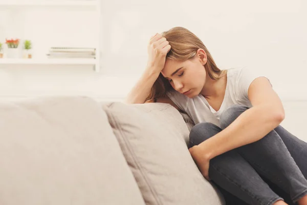 Casual blonde girl feeling pain while sitting on the couch — Stock Photo, Image