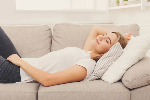 Happy young girl lying on sofa at home — Stock Photo, Image