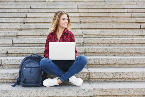 Student dívka sedí na schodech a práci s notebookem venku — Stock fotografie