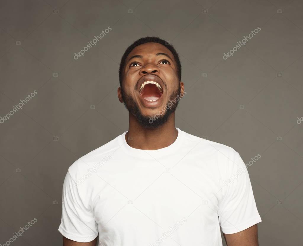 Black man expressing anger, feeling furious, shouting