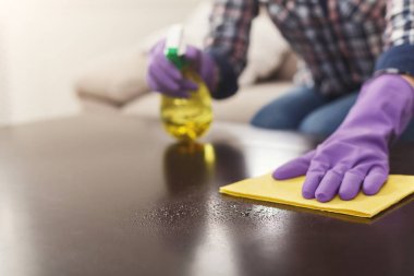 Sprey temizleyici ahşap yüzeyde kullanan kadın