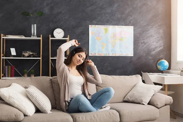 Joven chica sonriente en auriculares escuchando música — Foto de Stock