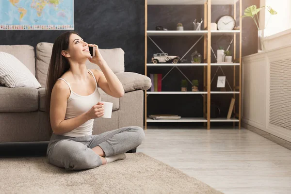 Woman talking on mobile and drinking coffee — Stock Photo, Image