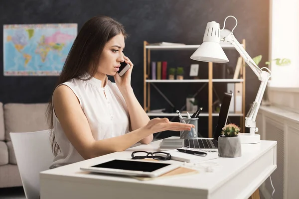 Young travel agent working on laptop and consulting on phone — Stock Photo, Image