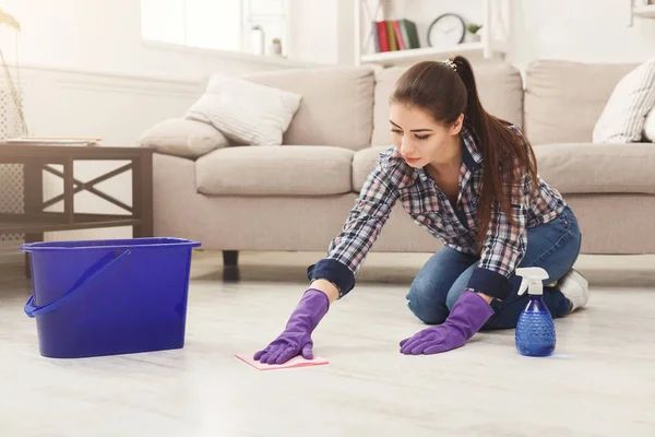 Concentrated woman polishing wooden floor — Stock Photo, Image