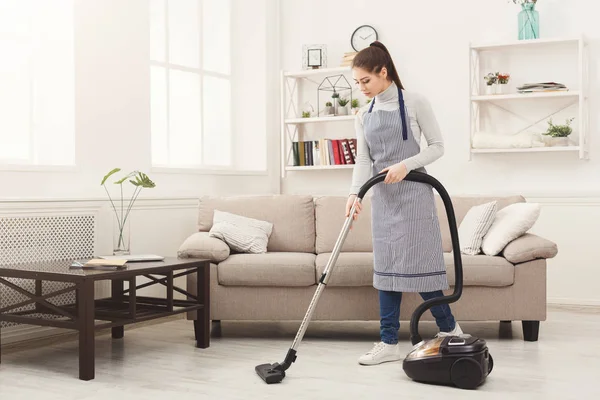 Молодая женщина уборка дома с пылесосом — стоковое фото