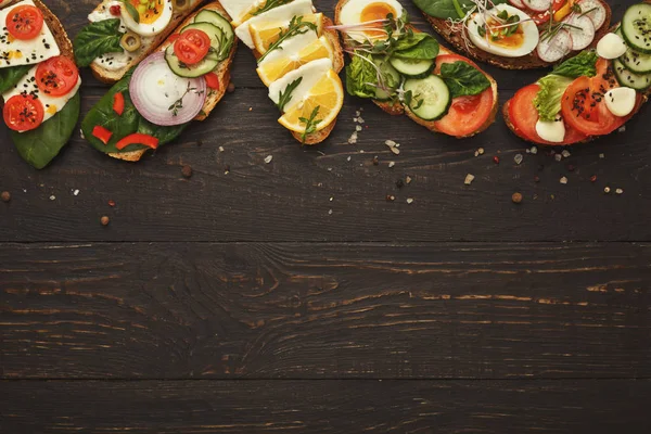 Разнообразие здоровых вегетарианских бутербродов на темной древесине, вид сверху — стоковое фото