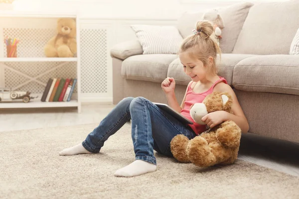Malá holčička s tabletem, sedí na podlaze doma — Stock fotografie
