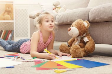 Gülümseyen küçük kız evde renkli kalemler ile çizim