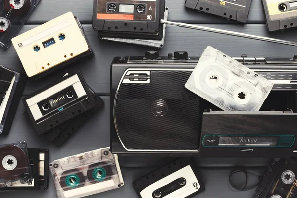 Купка старовинних аудіокасет і магнітофон на сірому фоні — стокове фото
