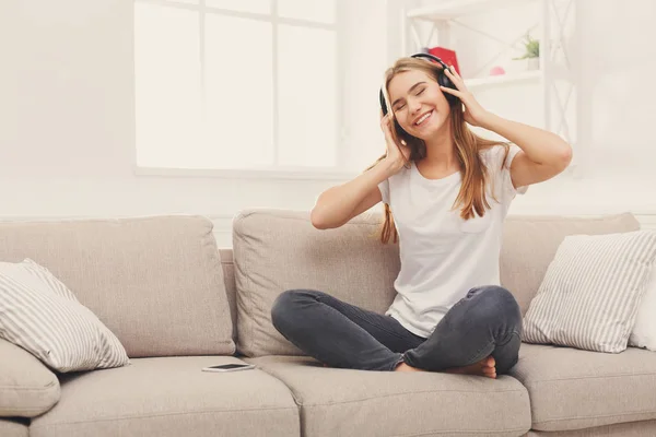 Boldog, fiatal nő, a fejhallgató a bézs kanapé — Stock Fotó