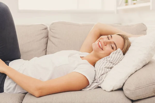 Happy young girl lying on sofa at home — Stock Photo, Image