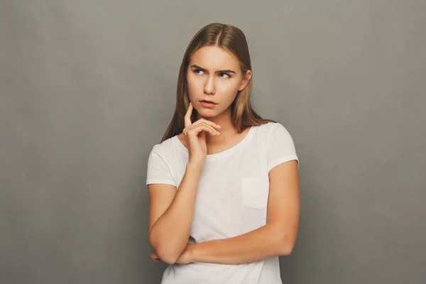 Konzentrierte Frau denkt auf grauem Hintergrund — Stockfoto