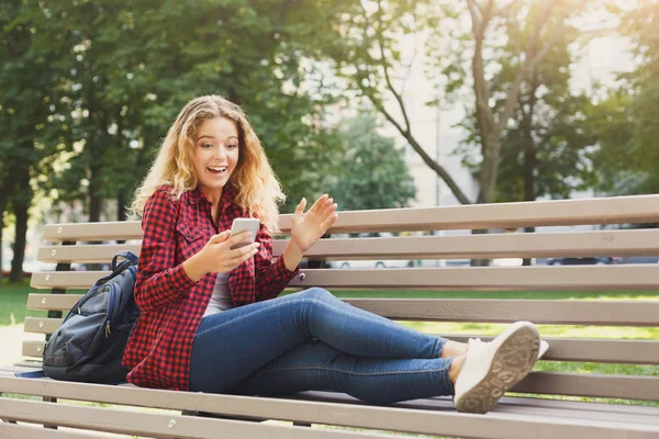 Mujer sorprendida leyendo noticias en el teléfono inteligente al aire libre — Foto de Stock