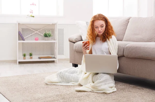 Mi godo il tempo libero a casa. Ragazza pensierosa con laptop e tazza di caffè — Foto Stock