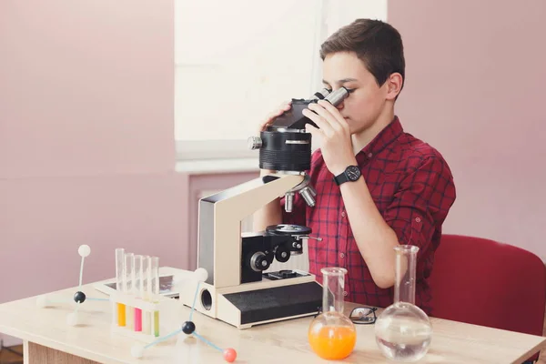 レッスンを顕微鏡で見ている男子生徒 — ストック写真