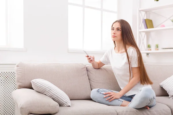 Молода жінка сидить на дивані з мобільним телефоном — стокове фото
