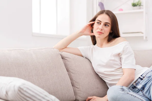 Young thoughtful woman sitting on sofa — Stock Photo, Image