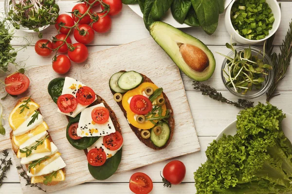 Variety of healthy vegetarian sandwiches on white wood, top view — Stock Photo, Image