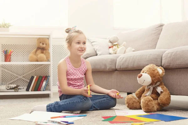 Gülümseyen küçük kız evde renkli kalemler ile çizim