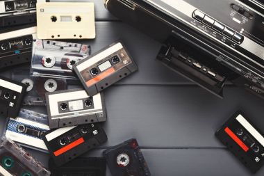 Heap of vintage audio cassettes and tape recorder at gray background clipart