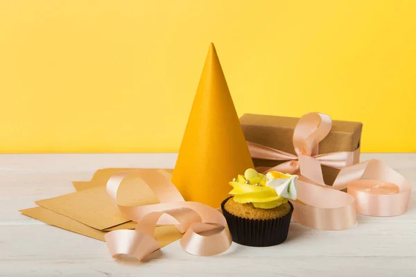 Läcker cupcake och gåva på gul bakgrund — Stockfoto