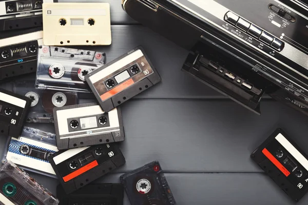Heap of vintage audio cassettes and tape recorder at gray background — Stock Photo, Image