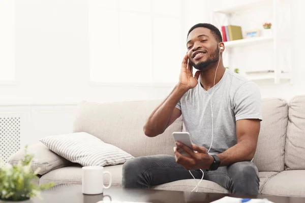 Young african-american man in earphones with smartphone — Stock Photo, Image
