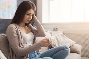 Üzgün kız onun gebelik testinin sonuçlarını okuma