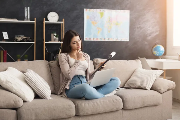 Doordachte vrouw met laptop en lezen van documenten — Stockfoto