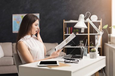 Şok kadın evde dizüstü bilgisayarda çalışan ve belgeleri okuma