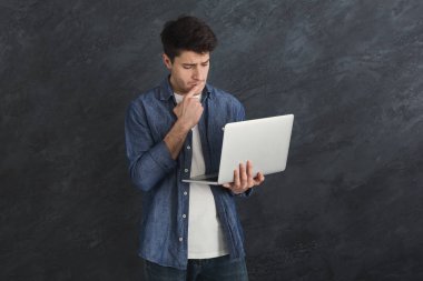 Young serious man using laptop computer clipart