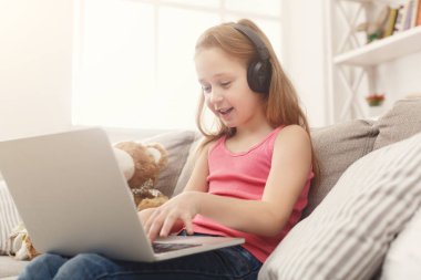 Ödev Kulaklığımda kanepede oturan laptop, sevimli küçük kız