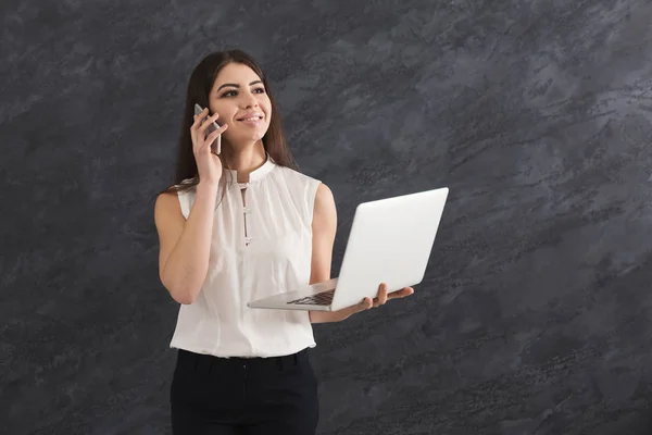 Woman talking on phone and holding laptop — Stock Photo, Image