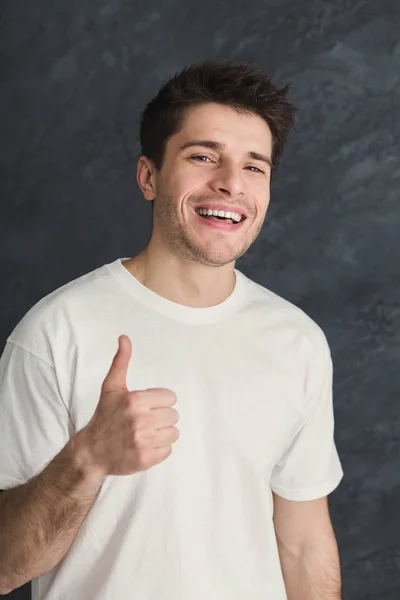 Junger lächelnder Mann mit erhobenem Daumen — Stockfoto