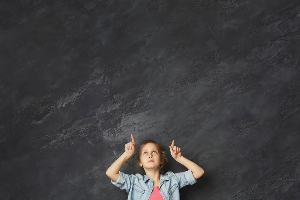 Casual menina mostrando o dedo para cima no fundo cinza — Fotografia de Stock