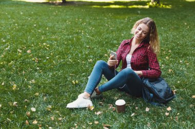 Oturma ve açık havada smartphone kullanarak güzel kadın